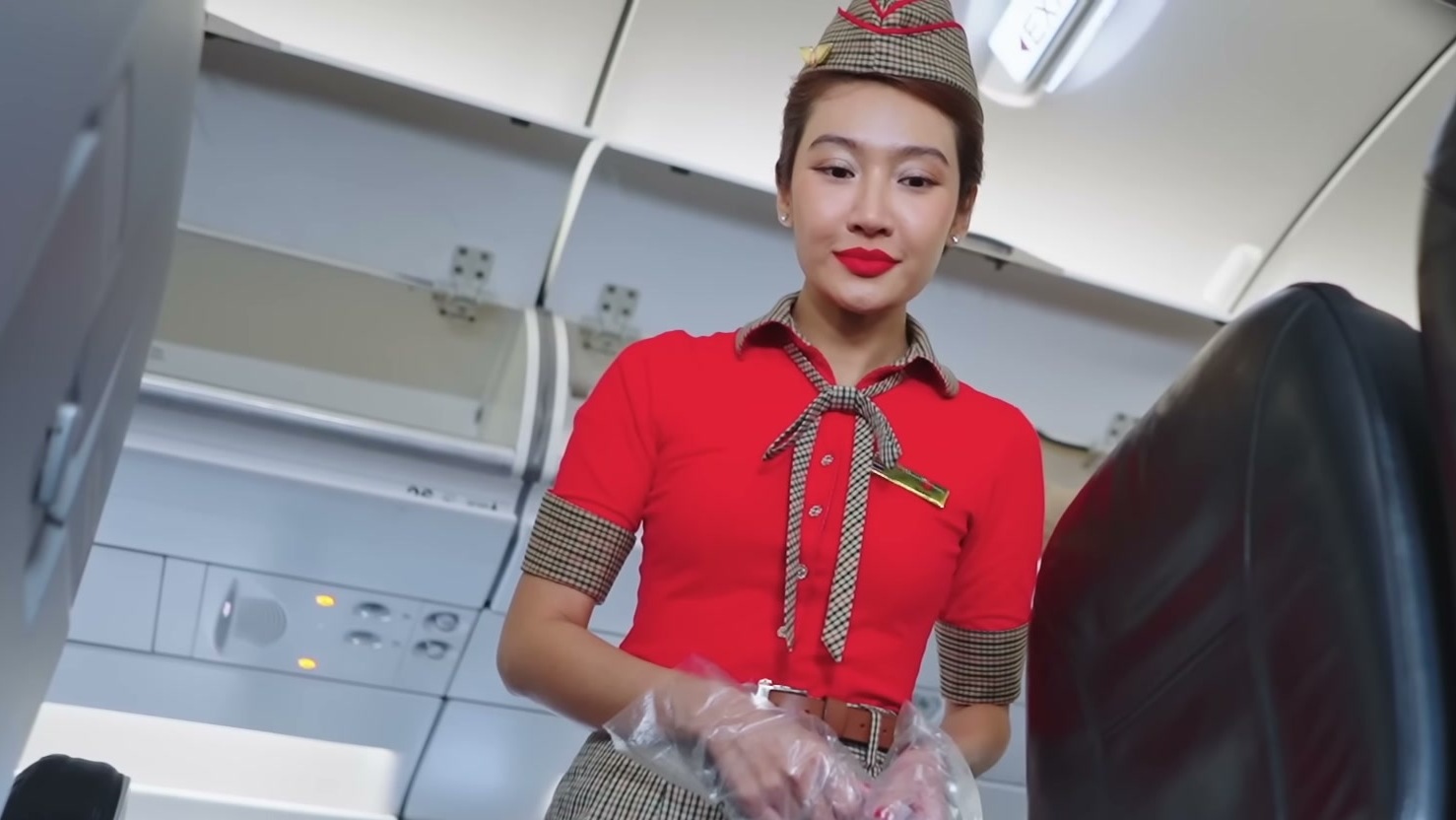 ลูกเรือไทยเวียตเจ็ทใส่หมวกและถุงมือ เดินอยู่บนทางเดินในห้องโดยสาร